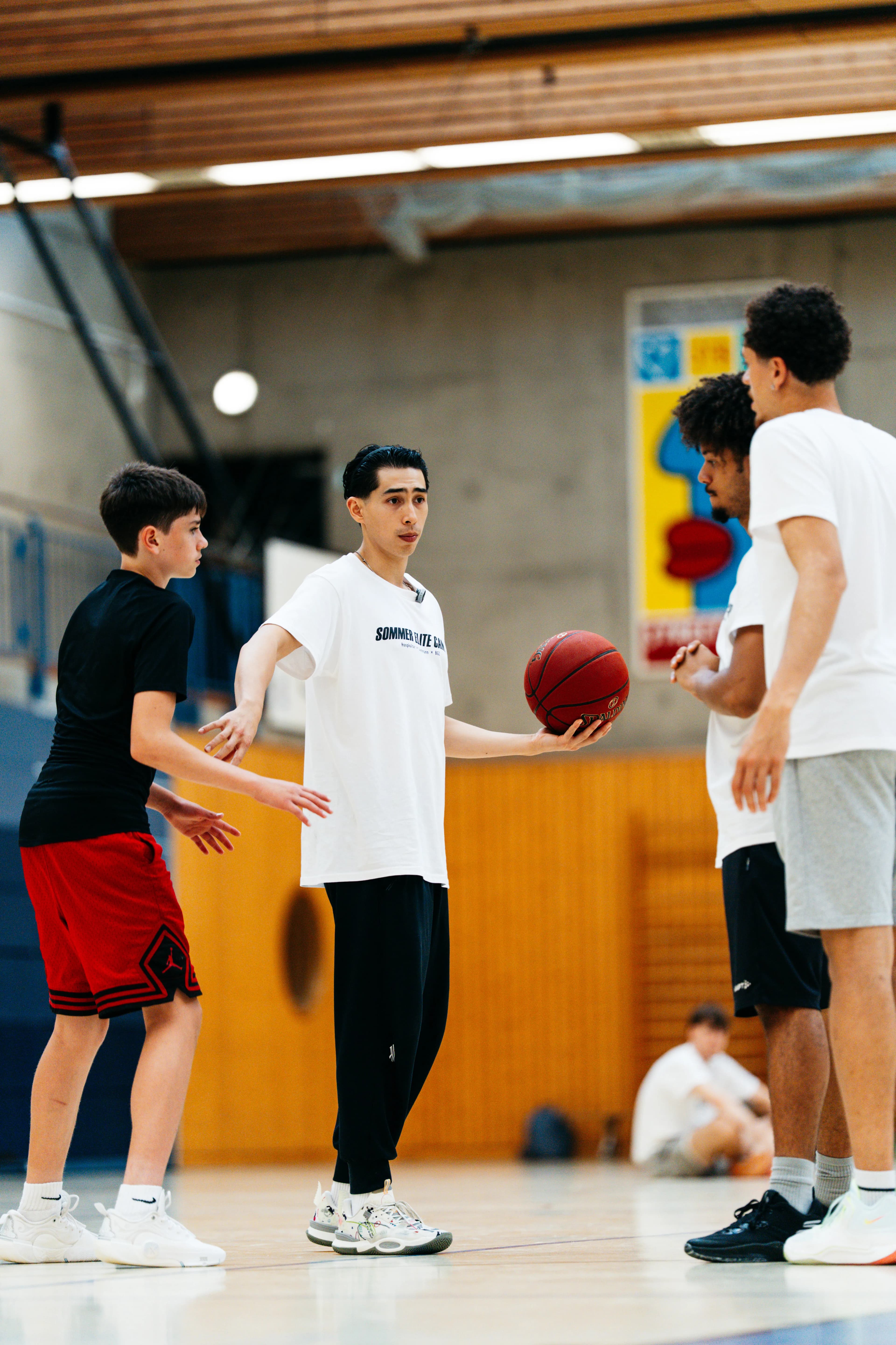 Players gather around as a drill is explained, ball in hand, at the Sommer Elite Camp